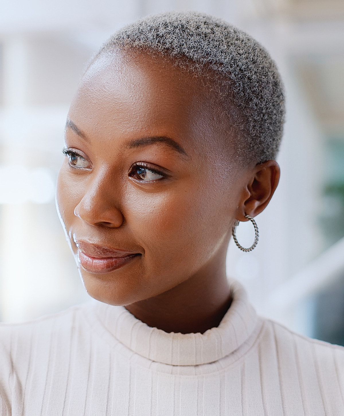 Smiling woman with short grey hair and earrings.