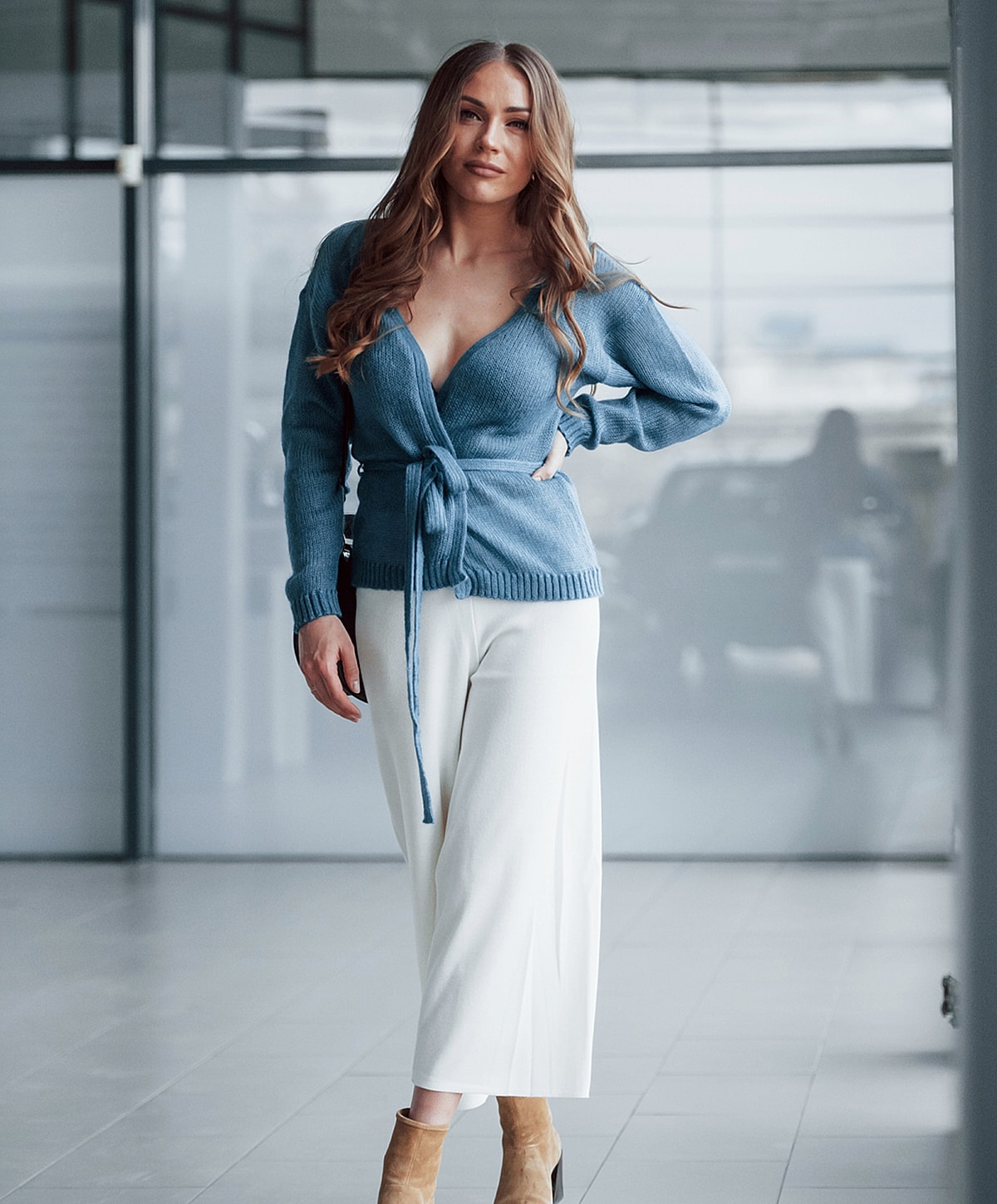 Woman in blue sweater and white pants indoors